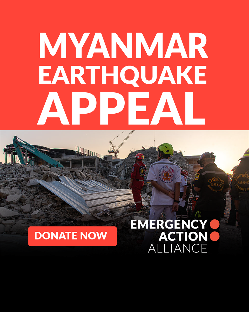 Several people standing at the site of a recent earthquake in Myanmar. Text saying: Myanmar Earthquake Appeal Donate Now Emergency Action Alliance